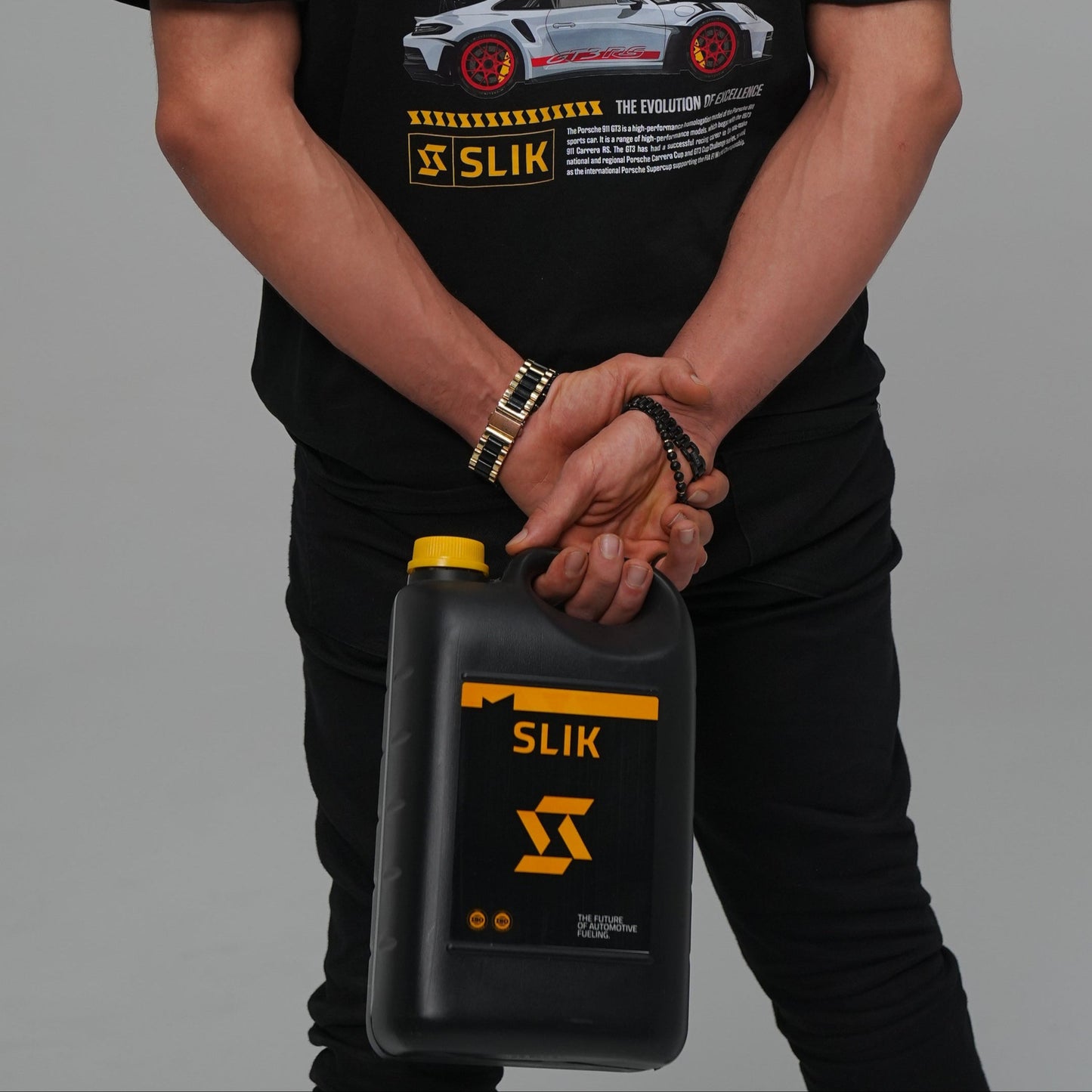 Person wearing a black t-shirt with graphics and text, holding a black container with yellow text.