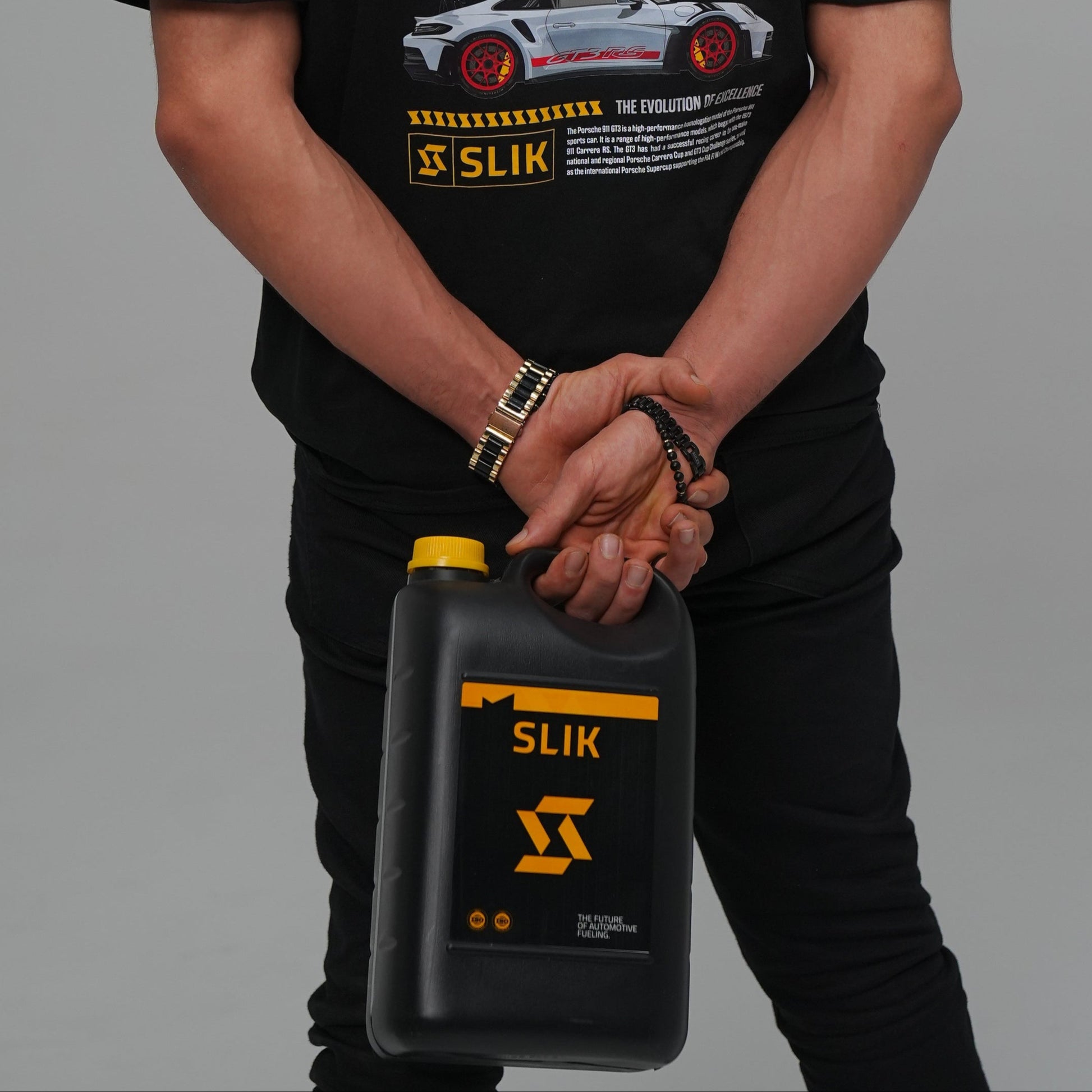 Person wearing a black t-shirt with graphics and text, holding a black container with yellow text.